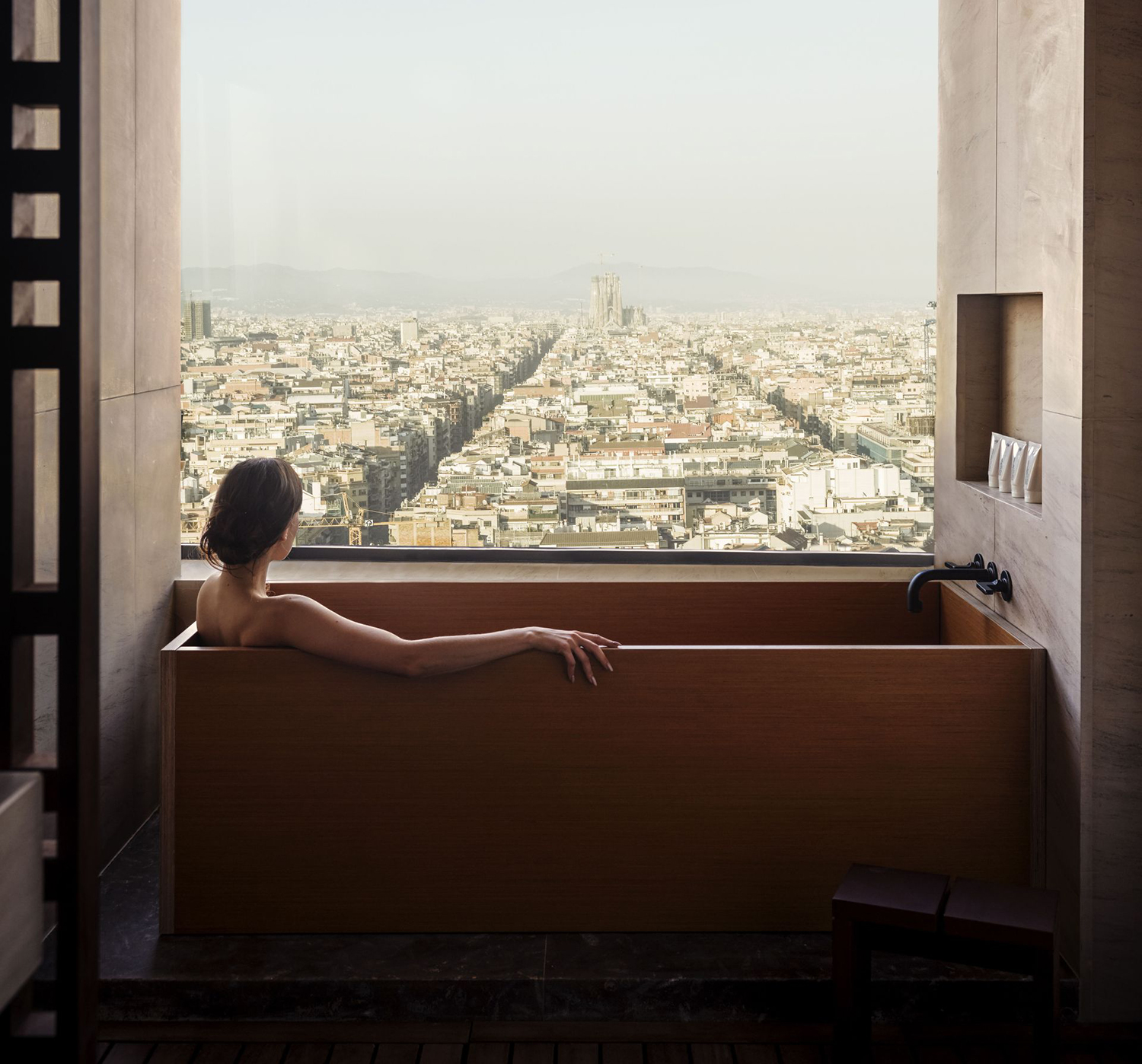 Woman having a bath watching Barcelona view through a big window