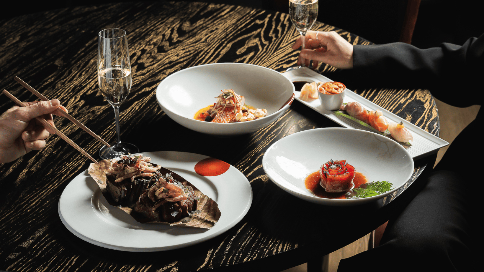 Colourful Japanese plates with champagne on a black table with gold colour