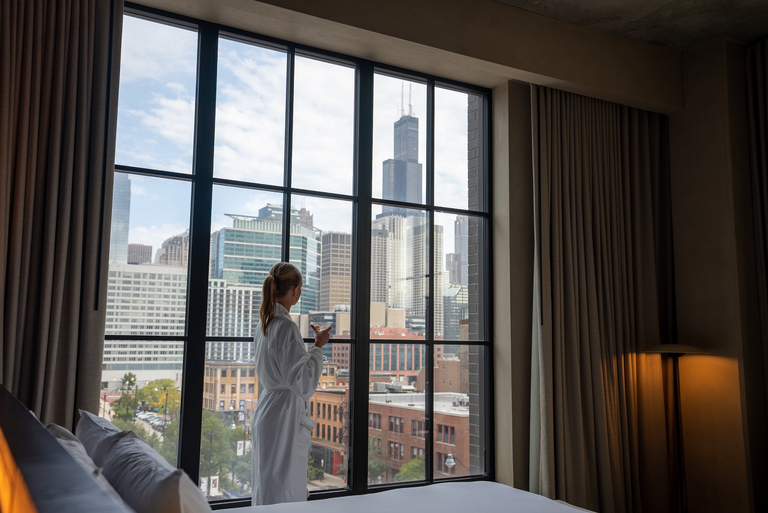 woman in a robe enjoying a beverage while looking out the window