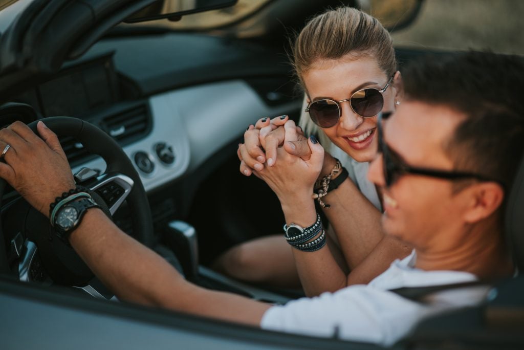 a couple driving in a car holding hands