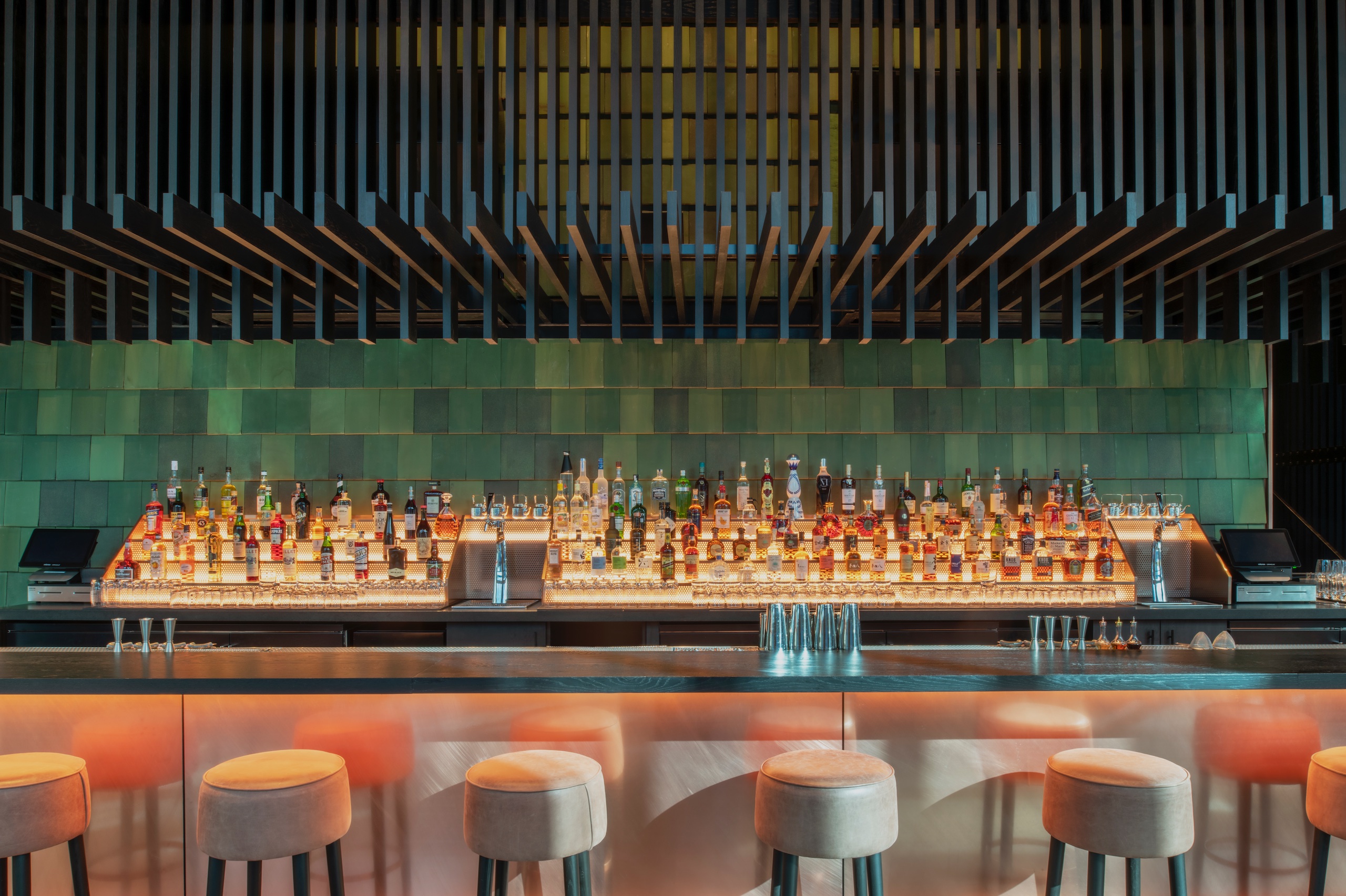 bar area with green backsplash and tan bar stools