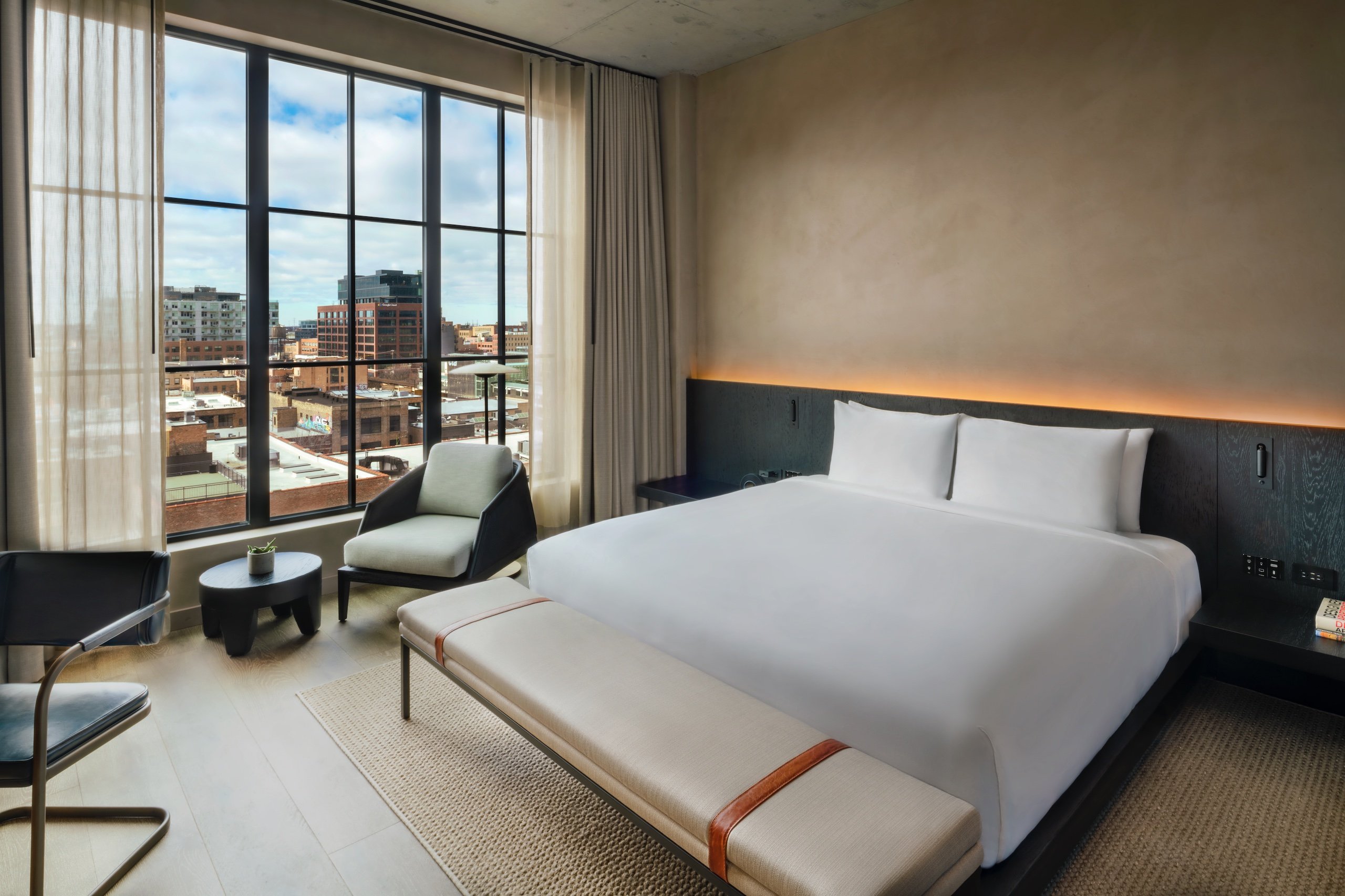 bedroom with sitting area and a large window with view of the city