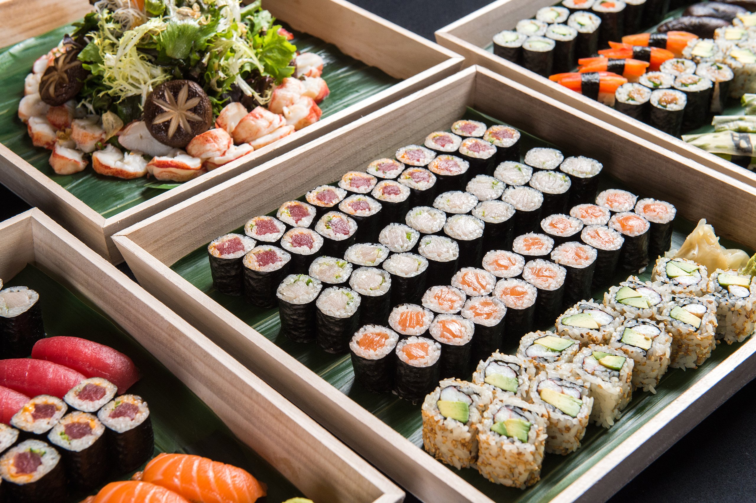 A colorful assortment of sushi neatly arranged in wooden trays, showcasing different rolls and fresh ingredients