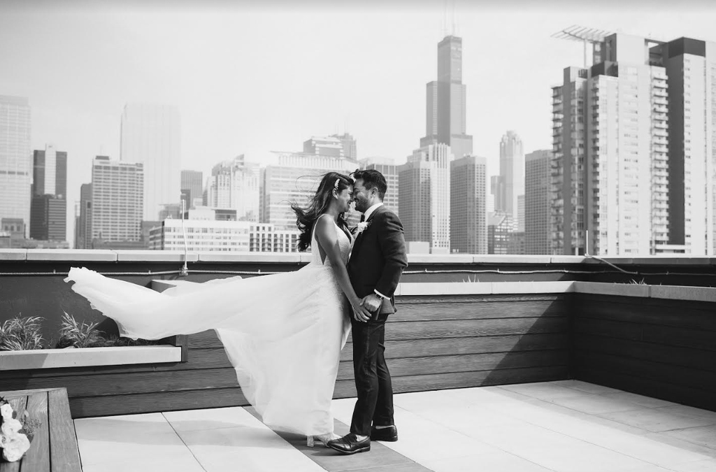 A bride and groom share a romantic kiss on a Chicago rooftop, with the city skyline in the background