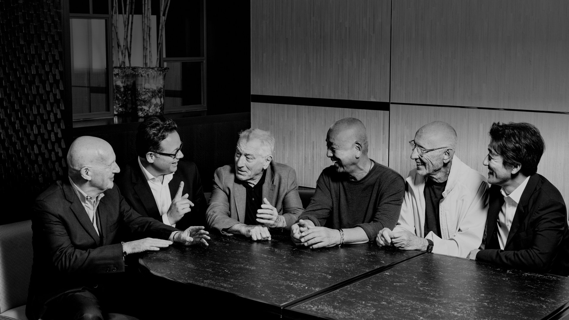 A group of men gathered around a table, engaged in conversation and sharing ideas in a friendly atmosphere