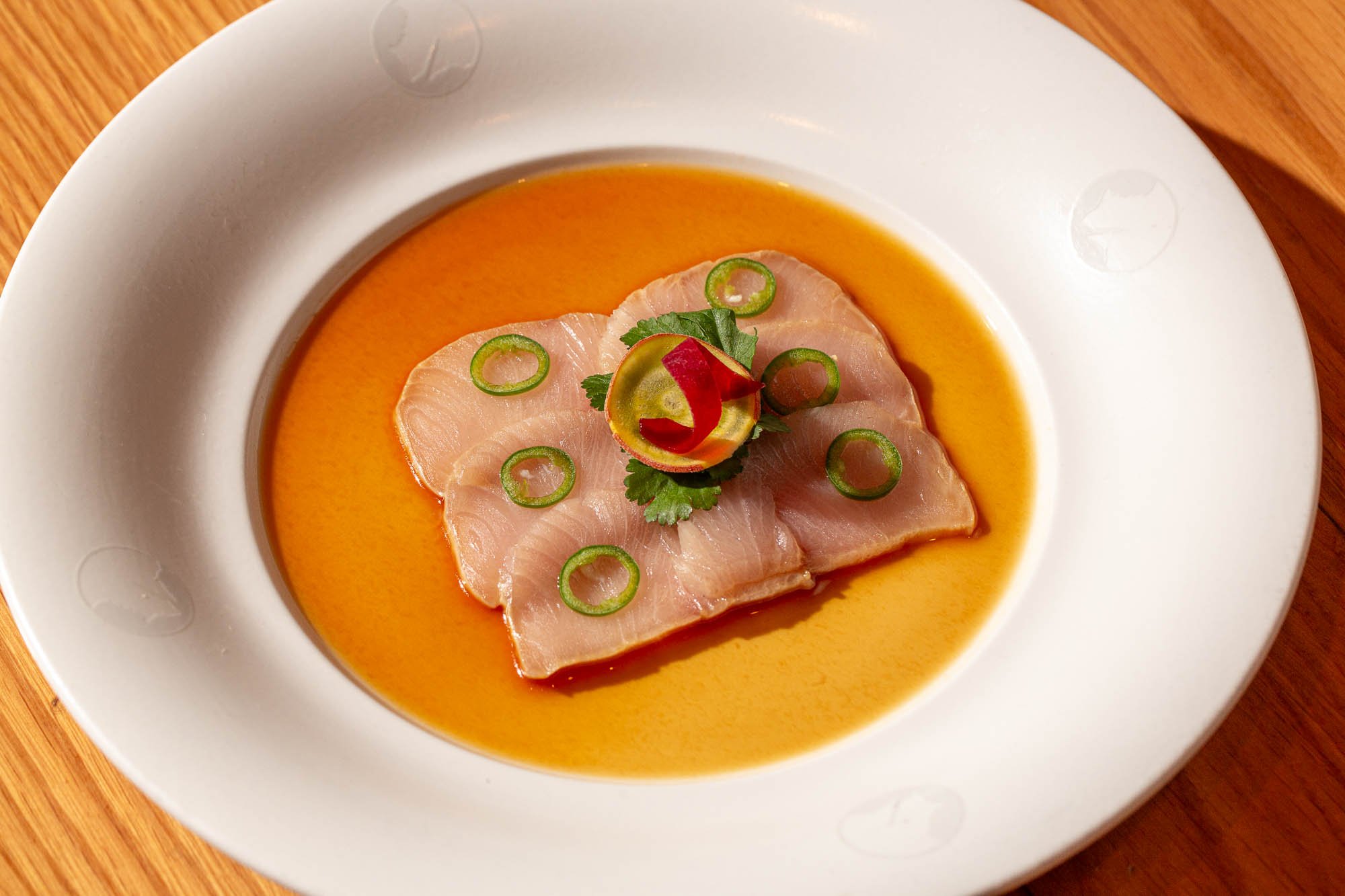Thinly sliced meat in a consommé, with garnish on top.