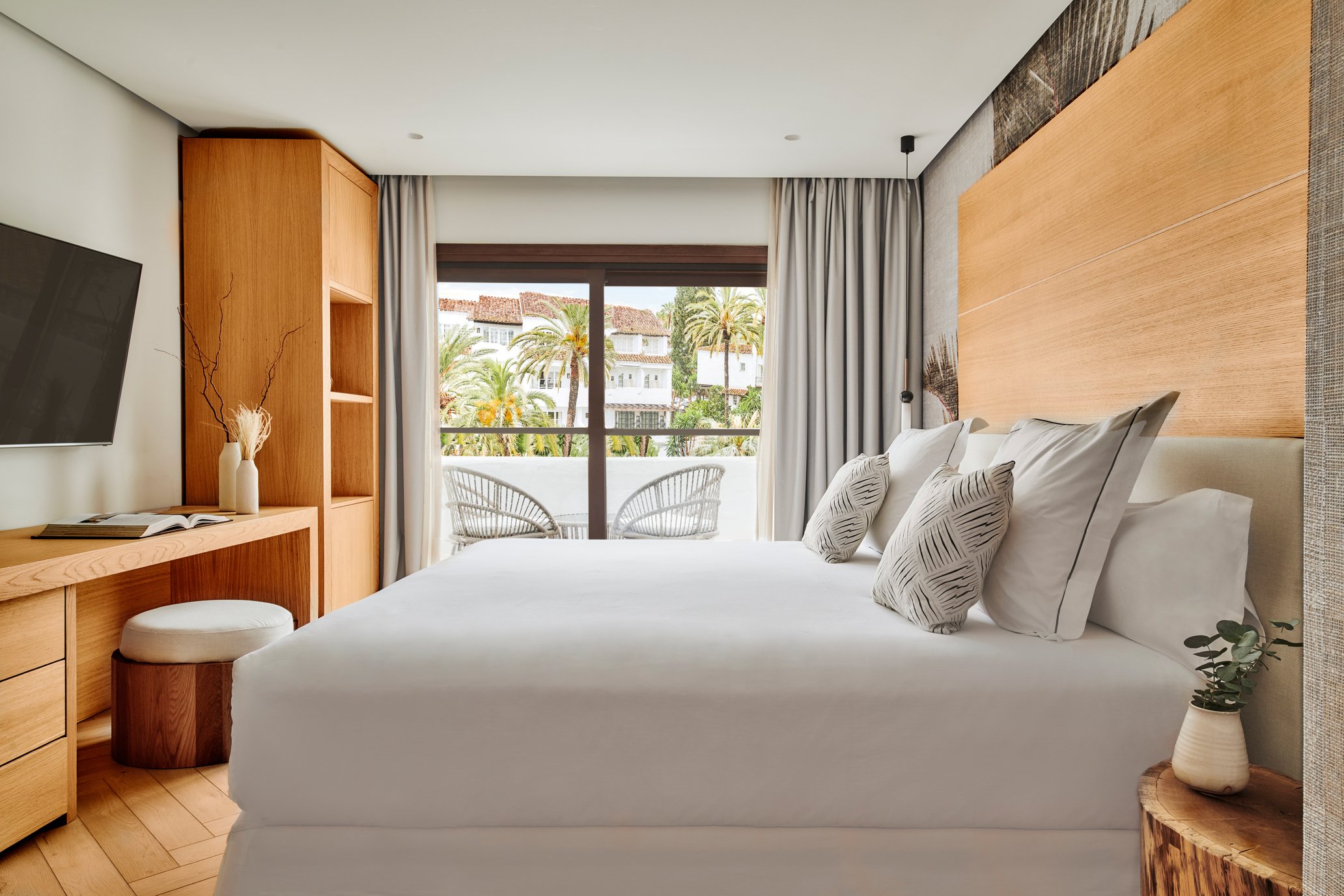 Cozy bedroom featuring a large bed, television, and a balcony with a beautiful view