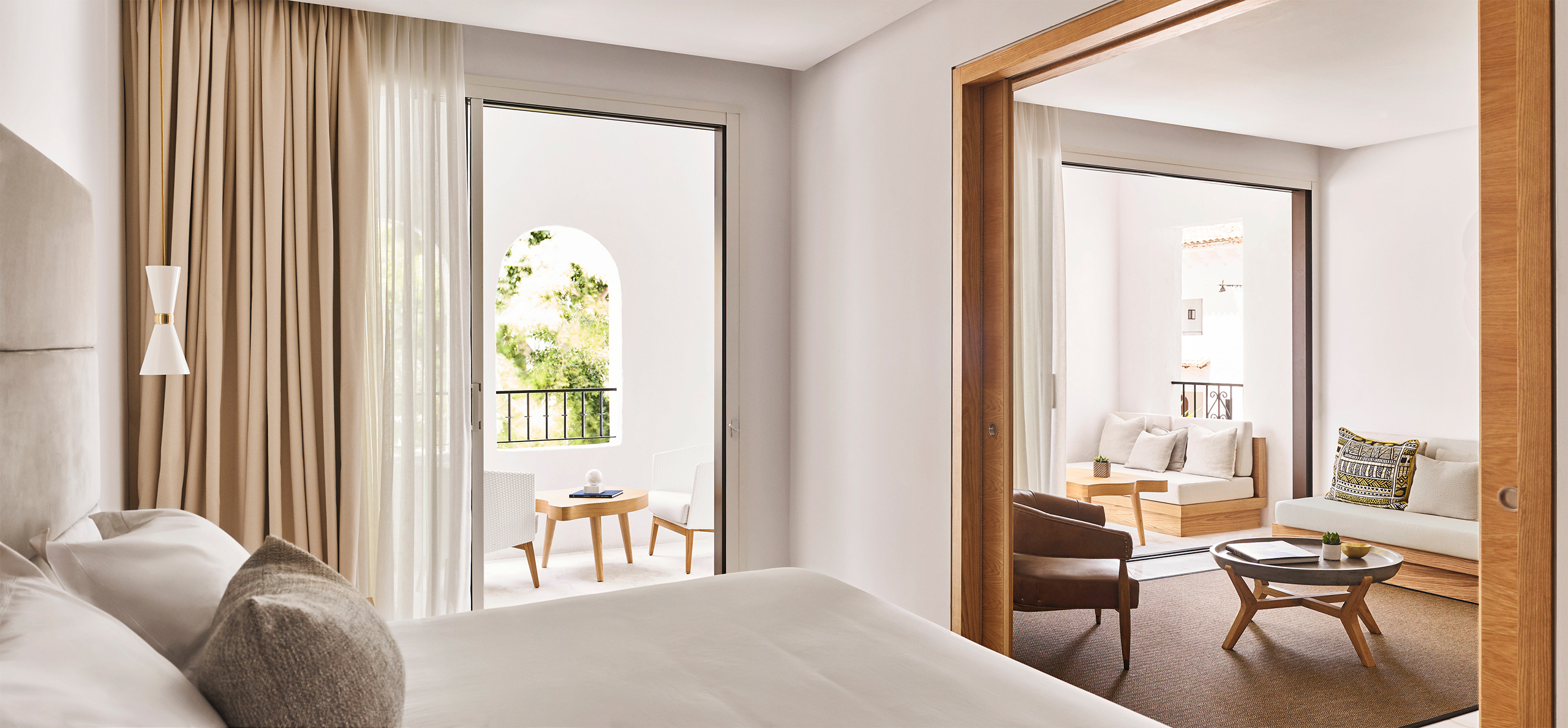 Bright hotel room showcasing a bed, a chair, and a sliding glass door that opens to a lovely outdoor space