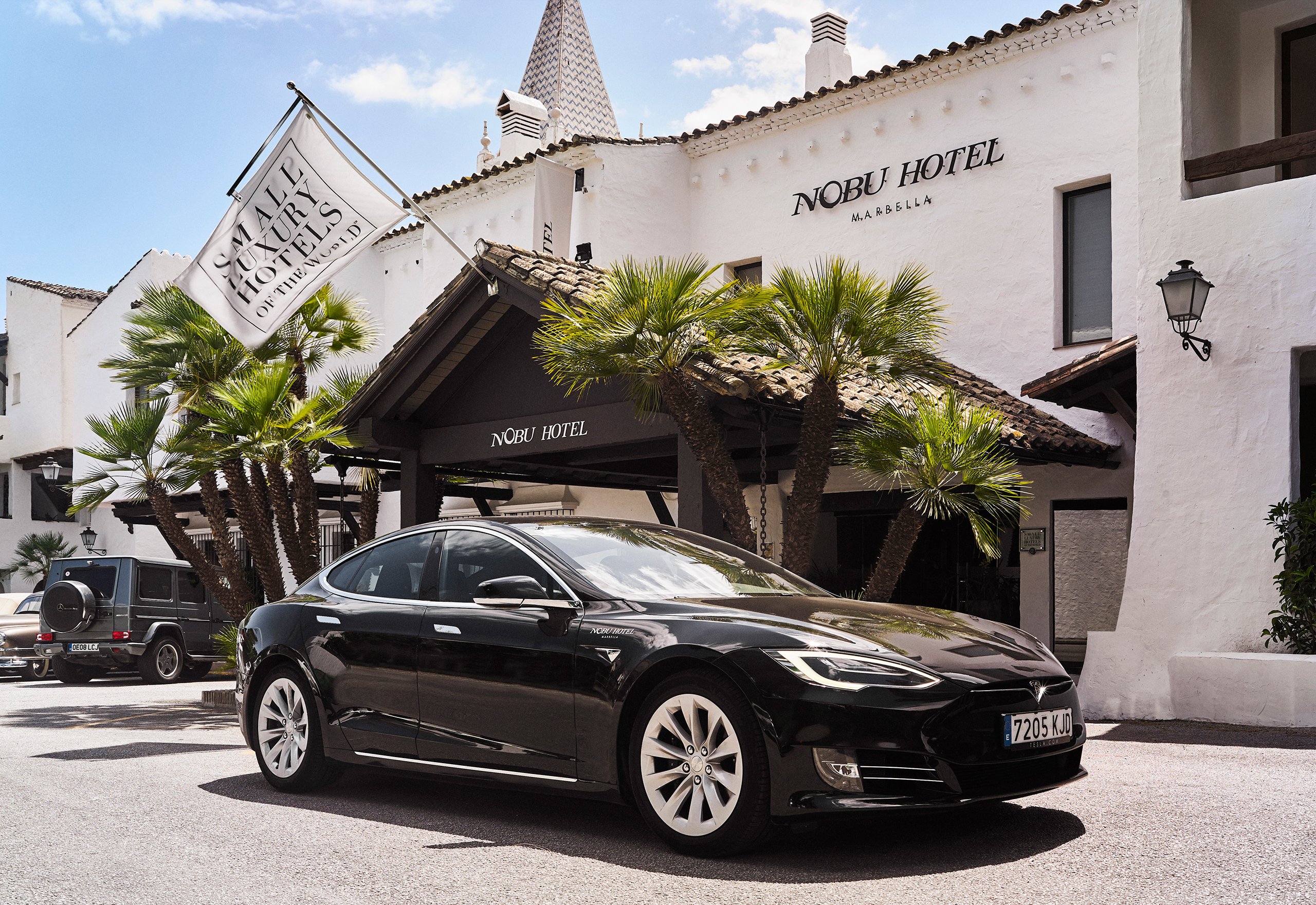 A sleek black car parked in front of a stylish hotel entrance, showcasing a modern urban vibe