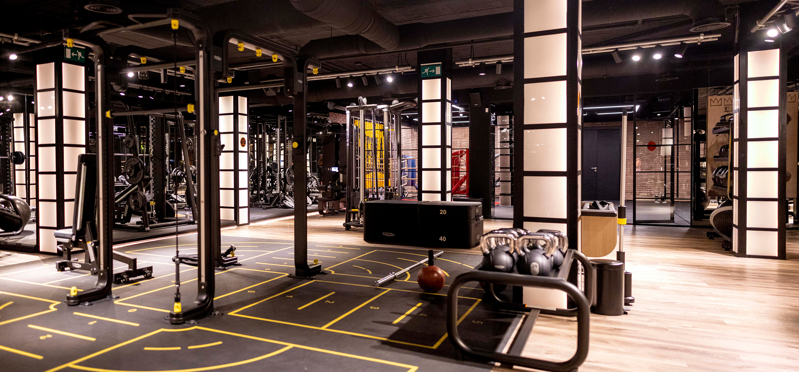 A well-equipped gym training area showcasing fitness gear on a stylish black and yellow floor