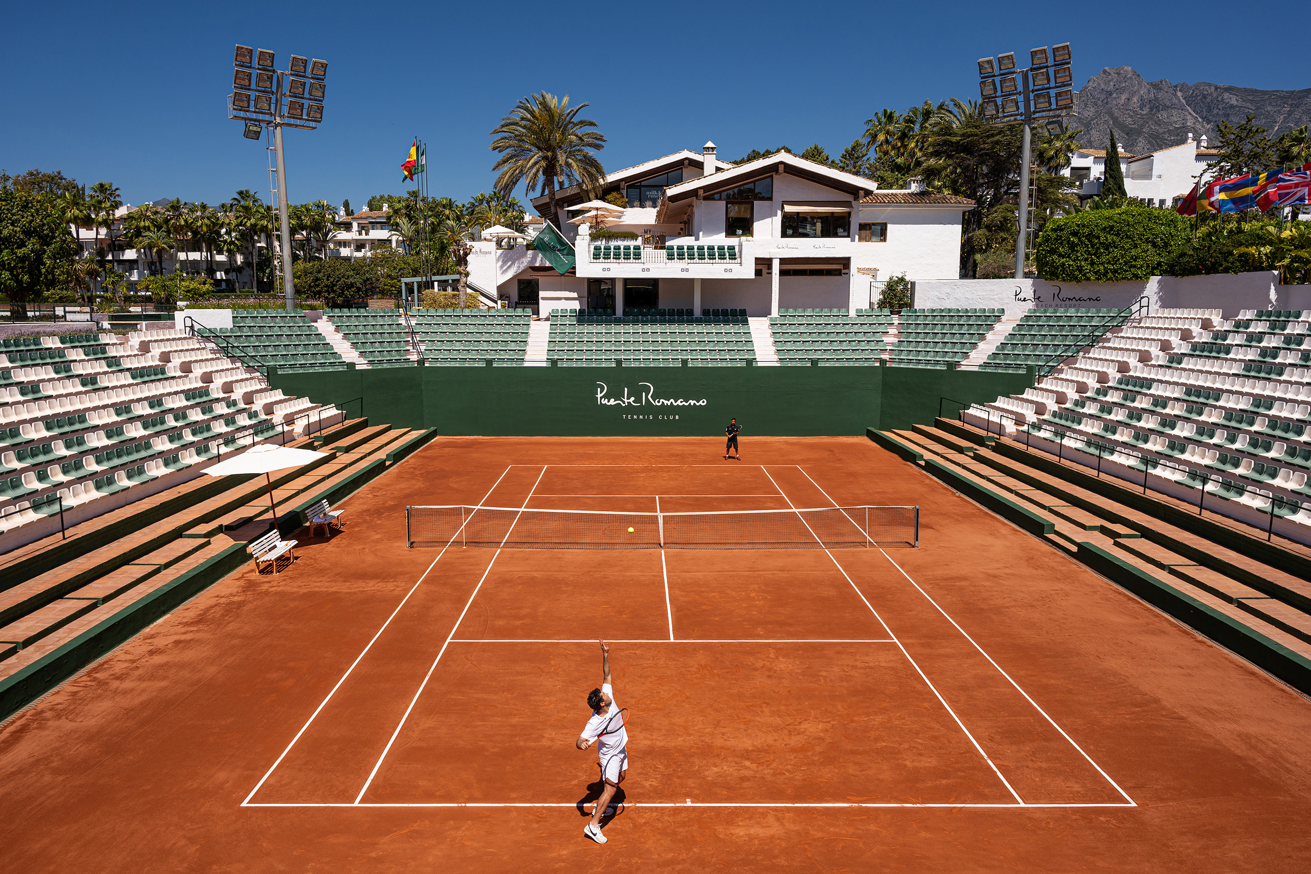 A sunny tennis court showcasing a lush green playing area and clear white boundaries, perfect for tennis enthusiasts