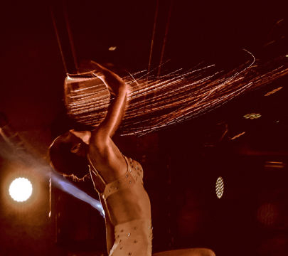 A woman in a white dress twirls on stage, embodying grace and joy as she dances for the audience