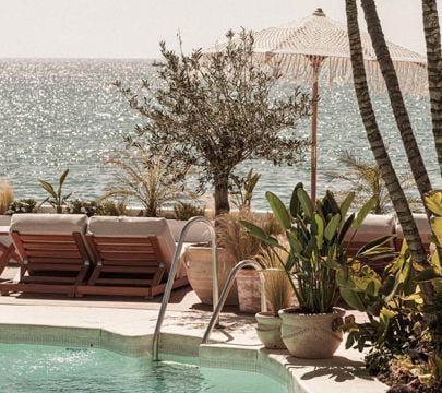 A tranquil pool area with comfortable lounge chairs and colorful umbrellas, set against the backdrop of the ocean.