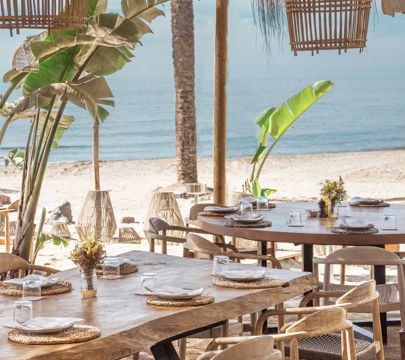 A charming restaurant on the beach, showcasing wooden tables and chairs for a delightful outdoor dining experience