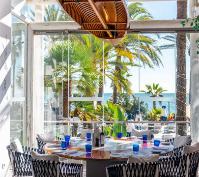 A seaside restaurant with a table and chairs, providing a picturesque view of the ocean and its gentle waves