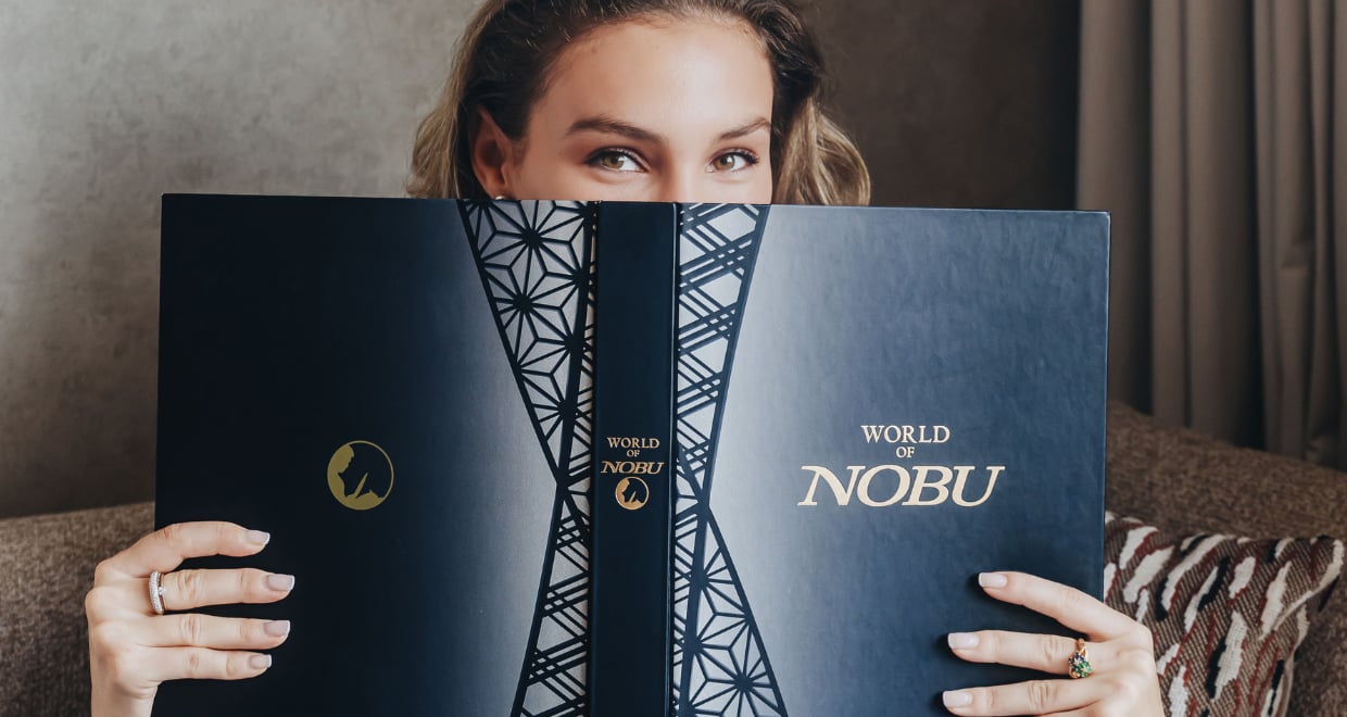 A cheerful woman showcases a book featuring the title 