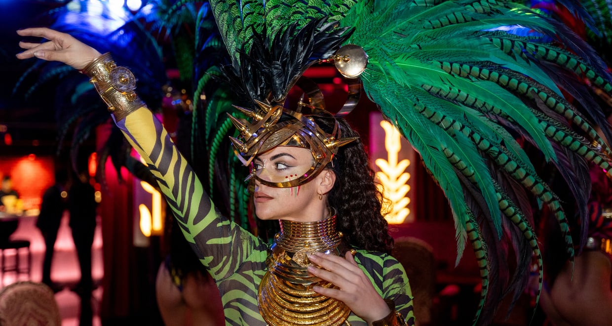 A woman dressed in an eye-catching costume, featuring a beautiful green feather headdress that highlights her vibrant style.