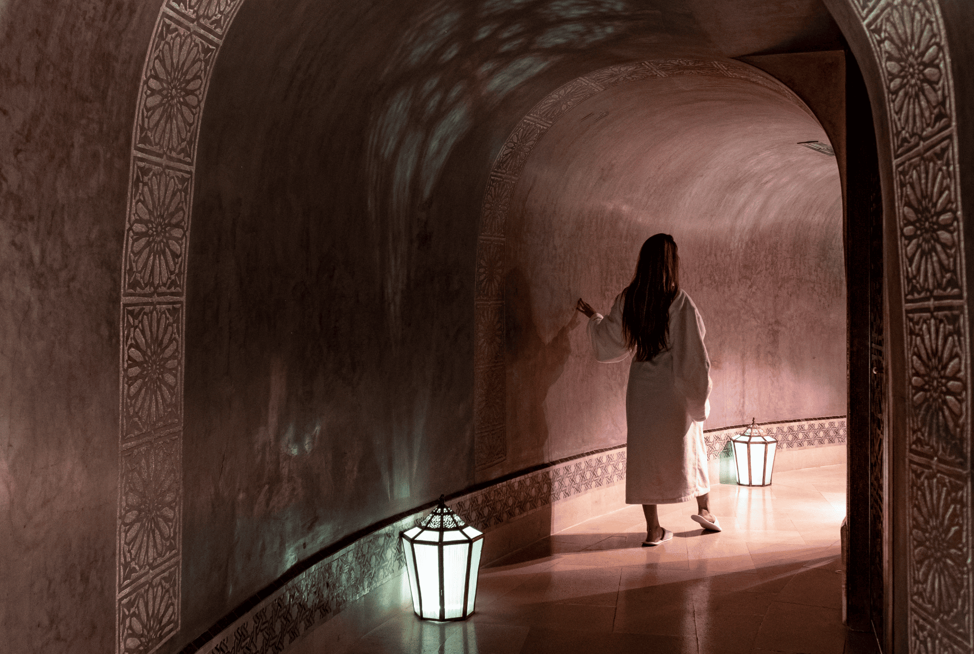 A woman dressed in a white robe strolls through a peaceful hallway, radiating tranquility and poise.