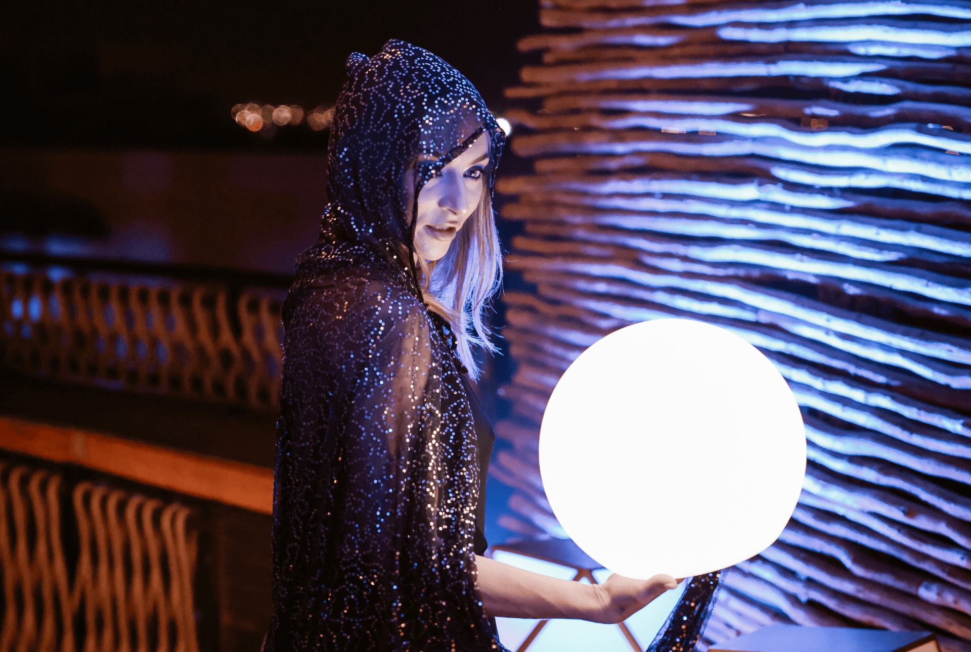 A woman in a stylish black dress gracefully holds a large ball, showcasing elegance and poise in her stance.