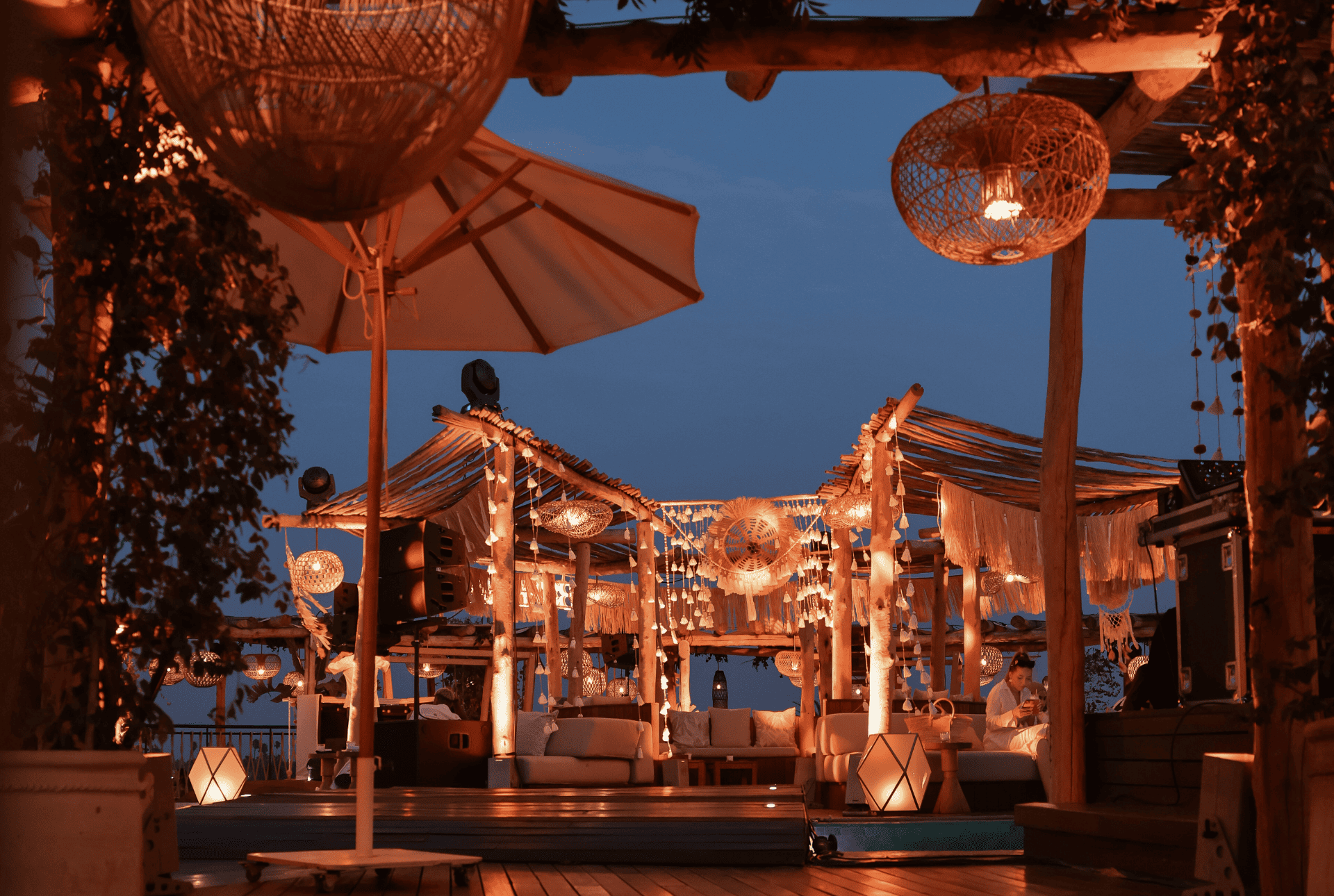 A cozy wooden deck adorned with glowing lights and colorful umbrellas, perfect for outdoor relaxation.