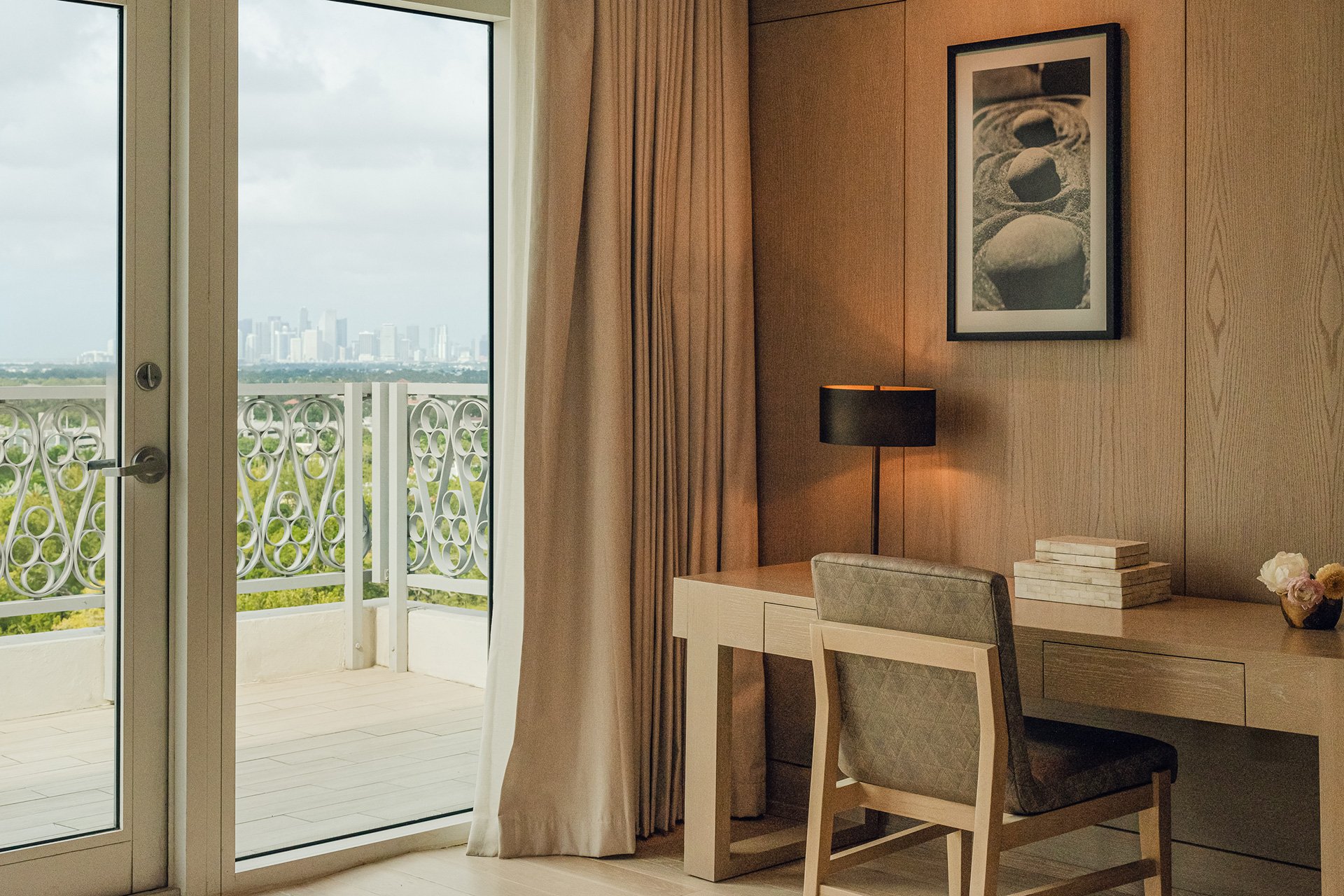 wooden desk and chair next to large balcony window