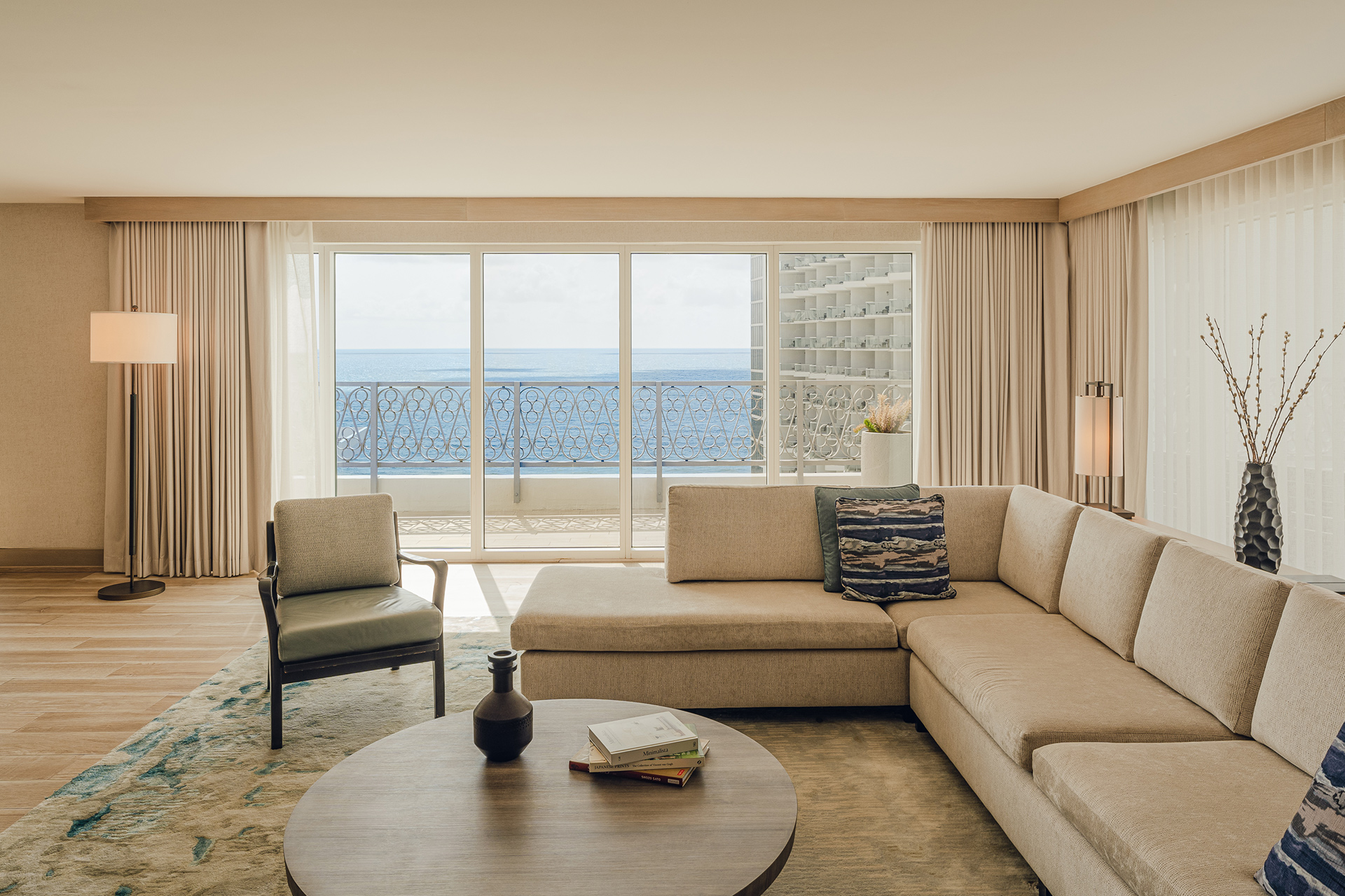 Large Sand Coloured couch and armchair with beach view through balcony window