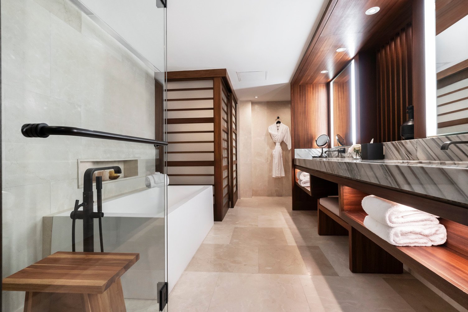 bathtub, wide sink, counter, and bathrobe in large modern bathroom