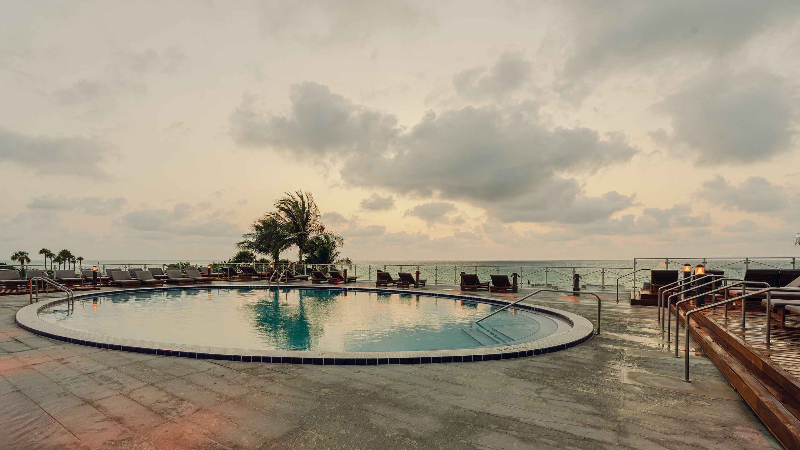 Round swimming pool, beach chairs and lighting with the beach view