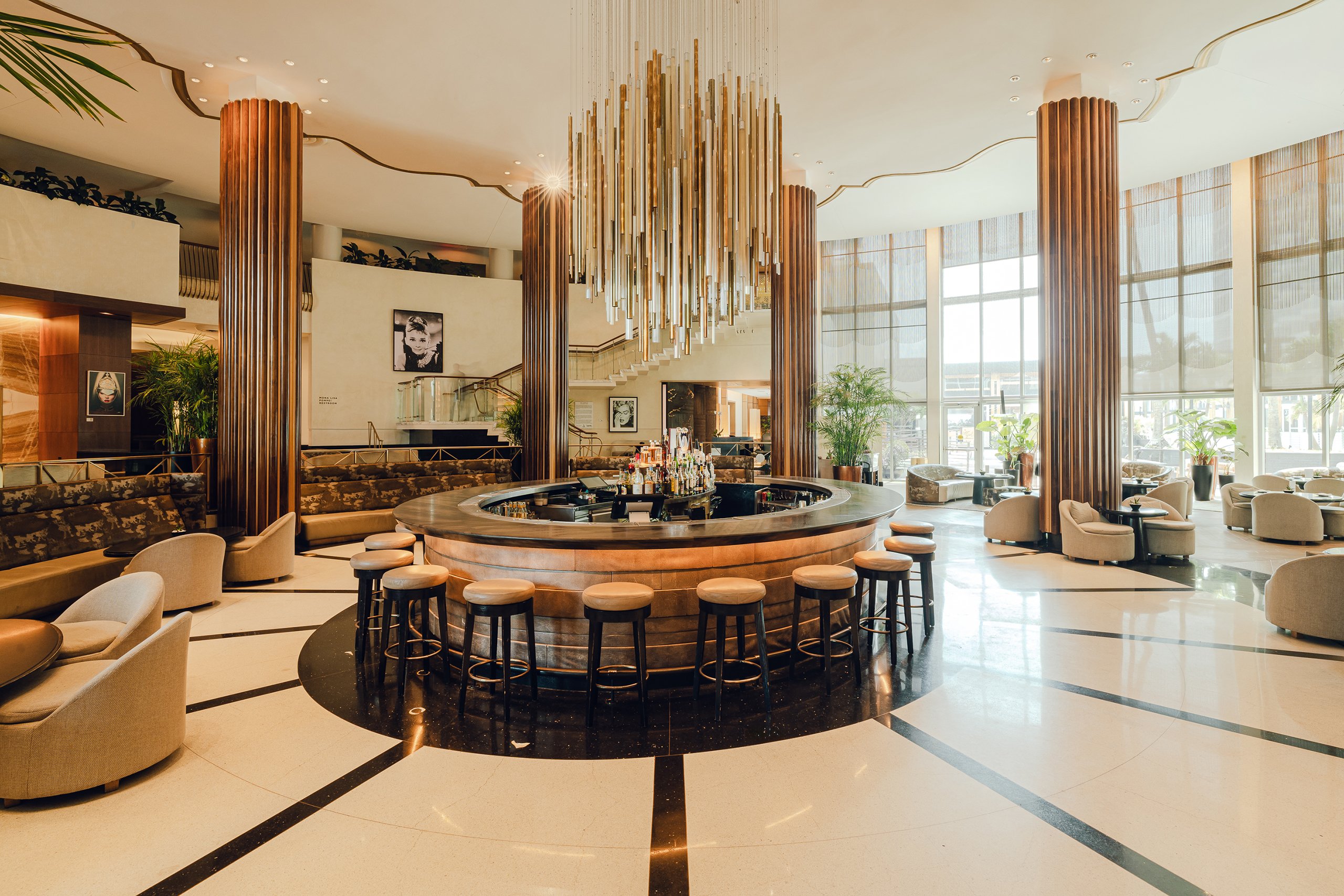 Bar area with various liquors, single couches and tables with gorgeous chandelier from lobby bar