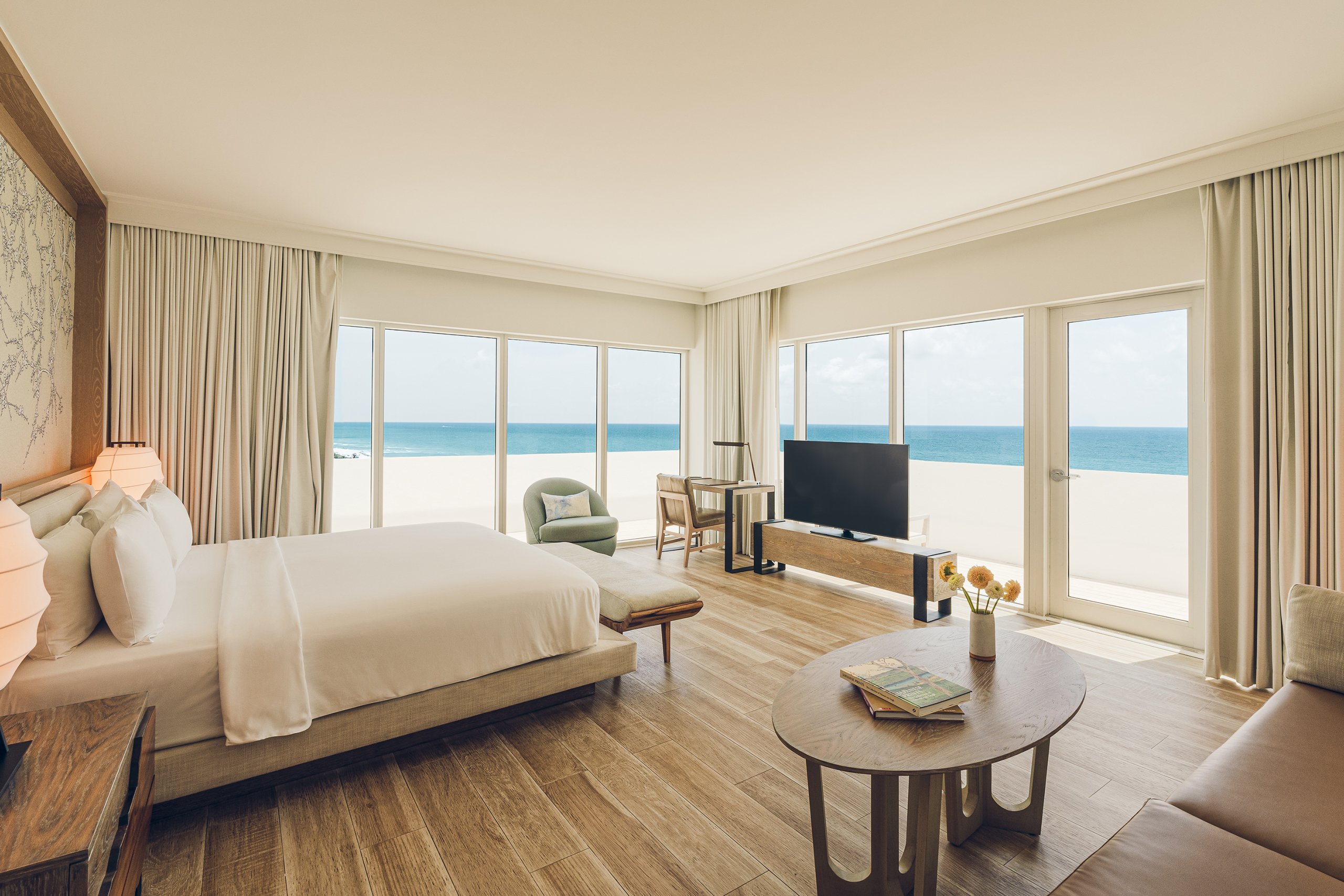 large bed, tv, and tea table with ocean view from the balcony