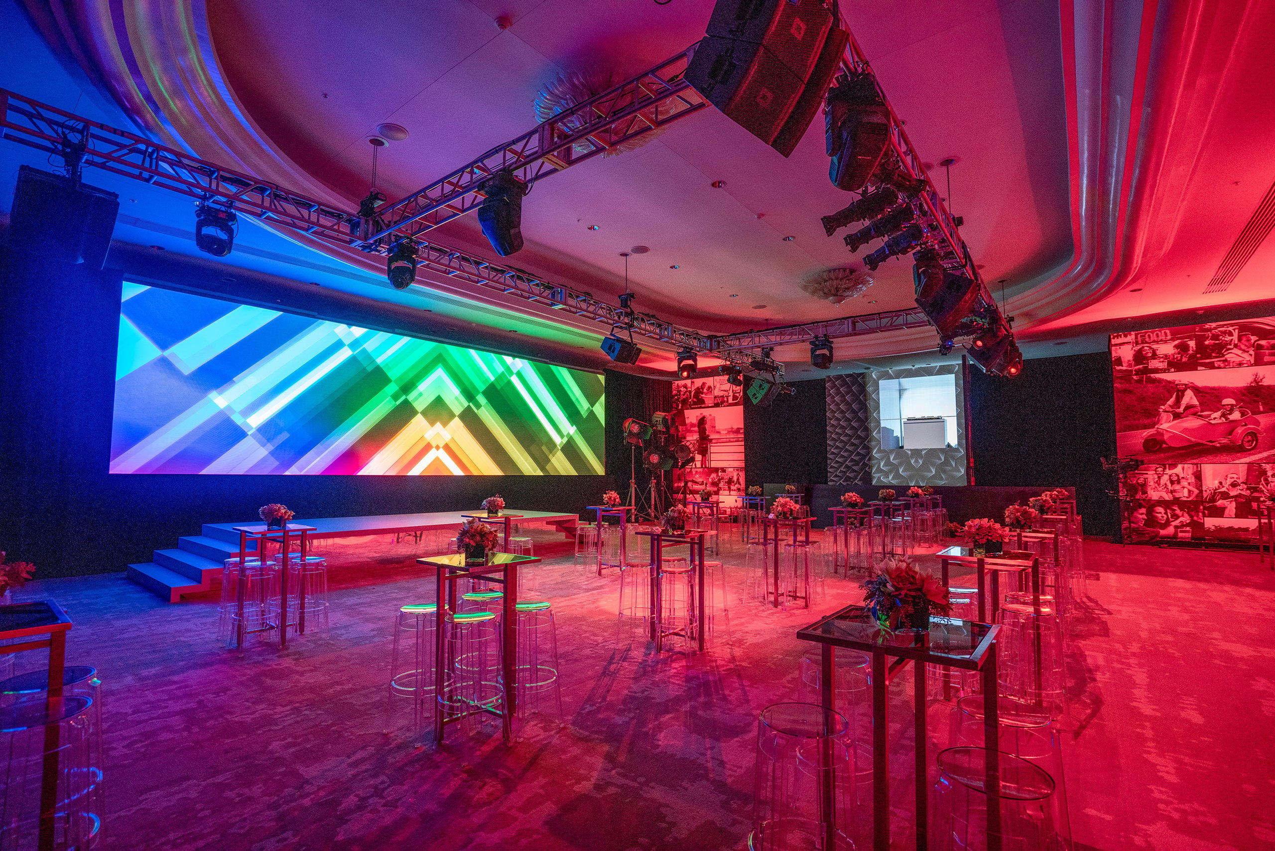 high chairs and tables with flowers from the meeting space in the red lighting