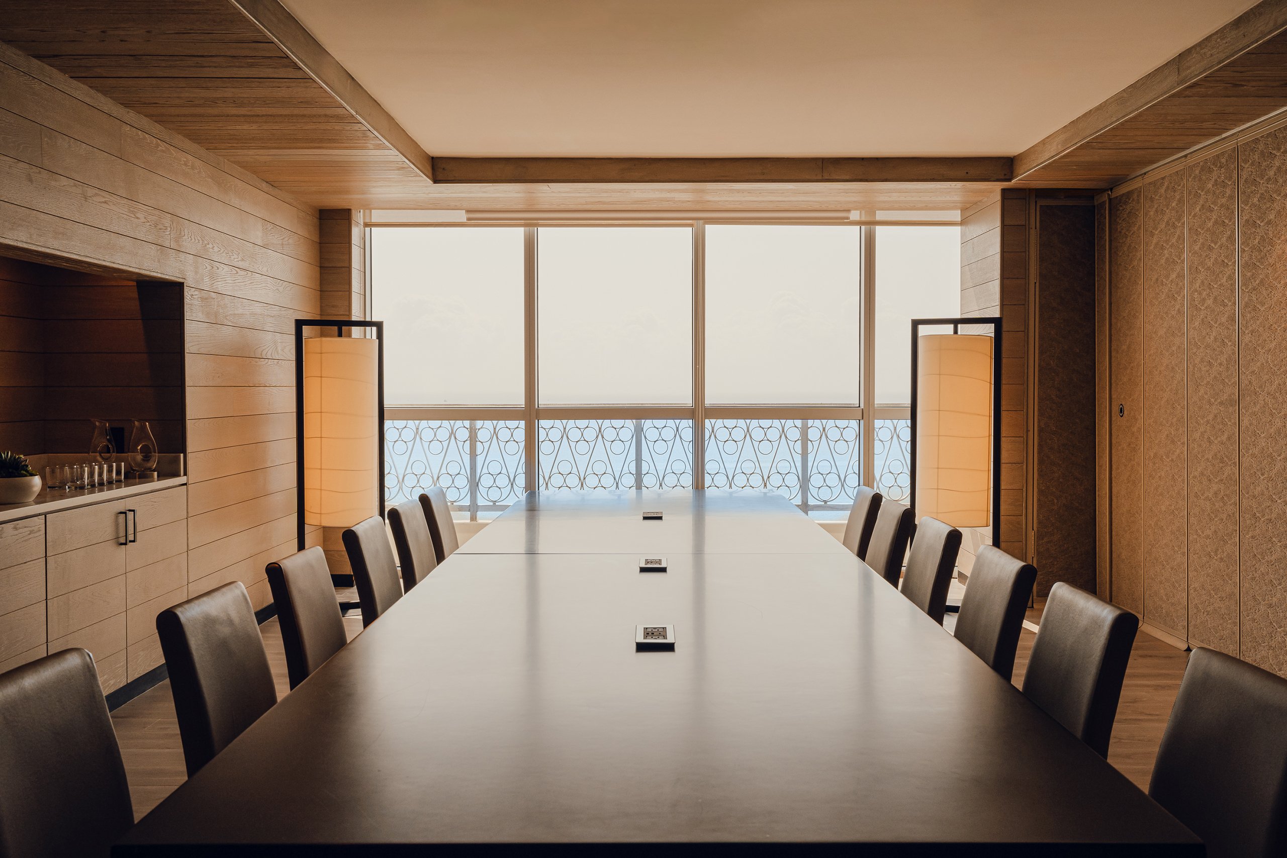 Wooden large desk with brown coloured chairs with ocean view