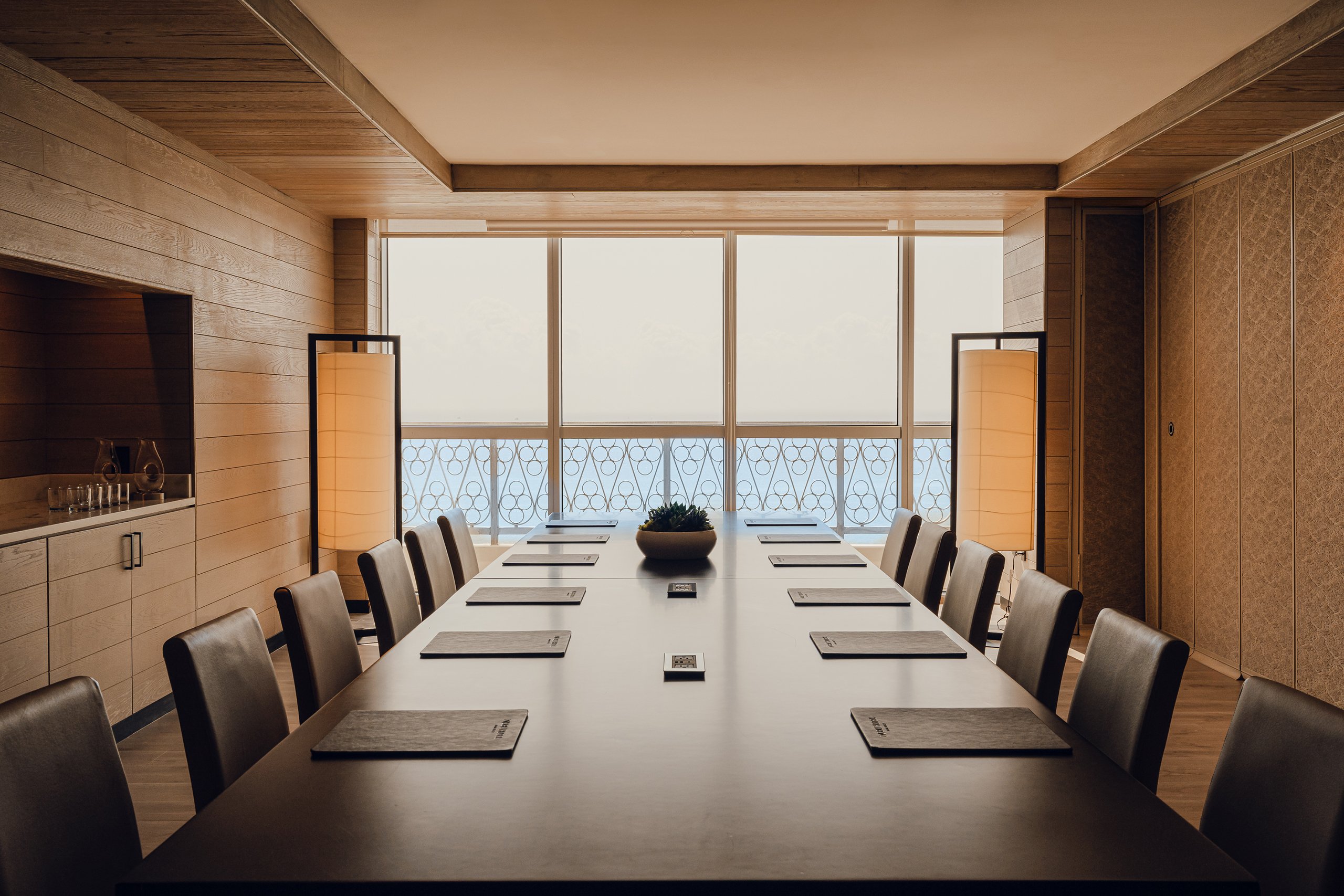 Wooden large desk with brown coloured chairs with ocean view