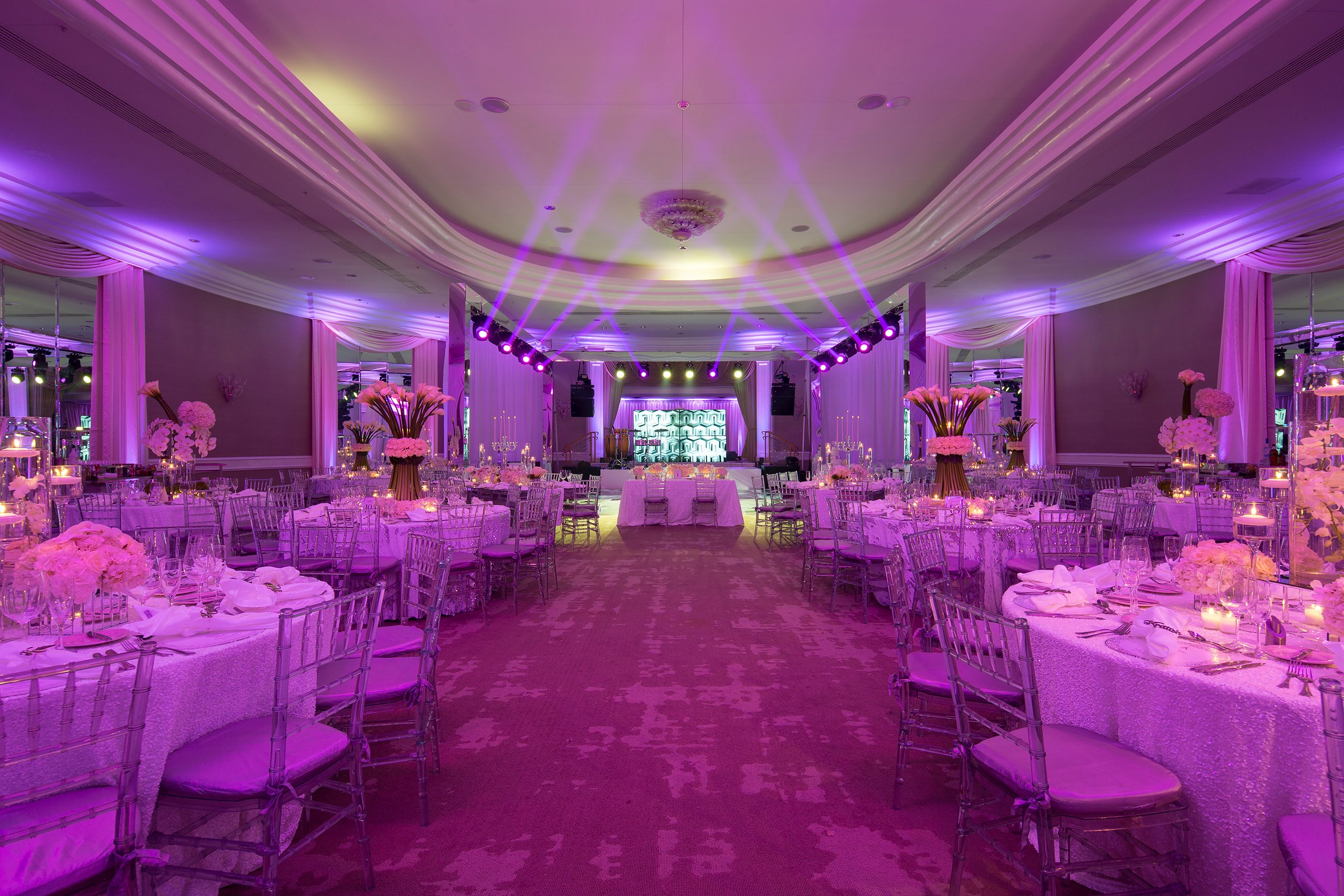 A beautifully decorated wedding reception illuminated with soft purple lighting, creating a romantic and enchanting atmosphere