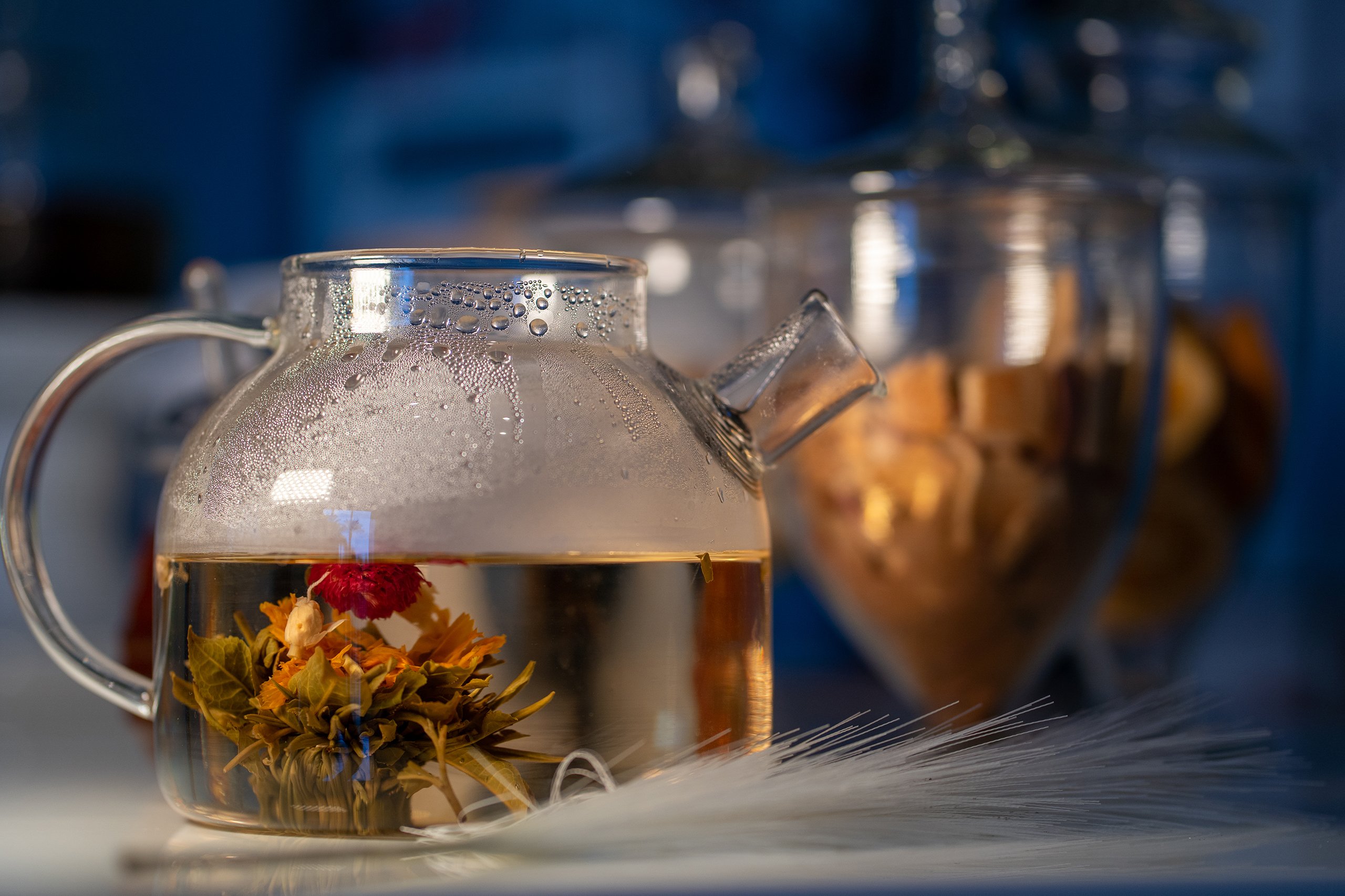 A transparent teapot brimming with water, featuring a beautiful flower inside, adding a touch of nature to the setting