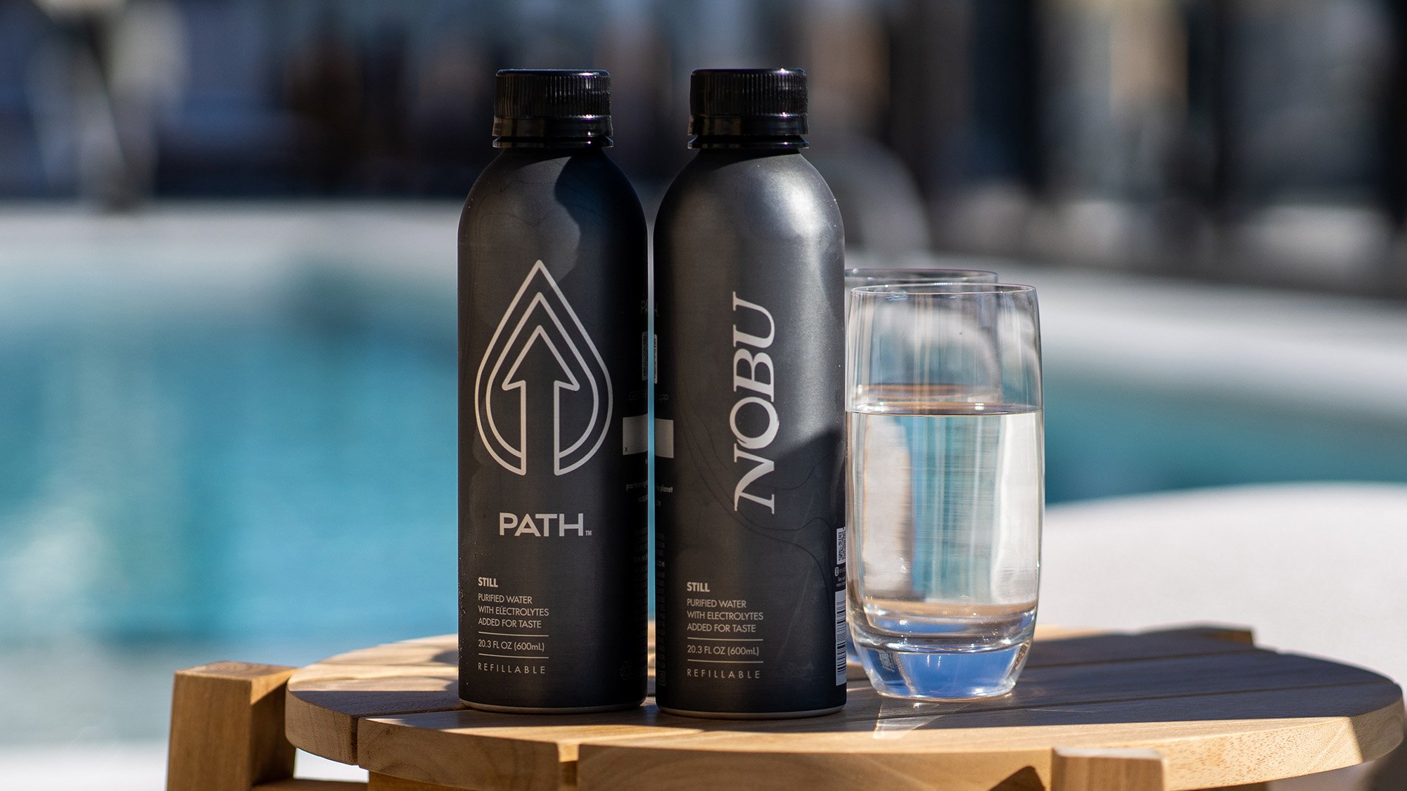 Two sleek Nobu Path water bottles side by side, showcasing their modern design and vibrant colors near the pool.