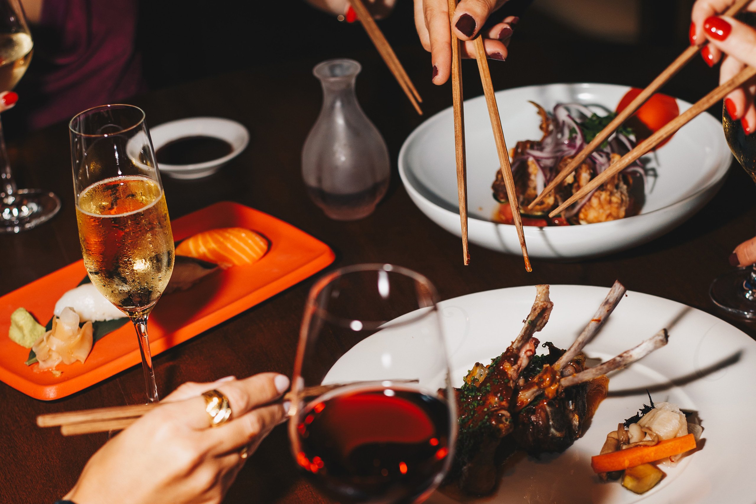 A gathering of people at a restaurant, engaged in a meal while using chopsticks to savor their dishes.