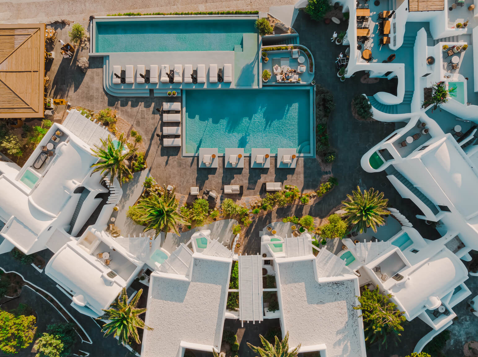 Stunning aerial shot of a resort showcasing a large swimming pool, surrounded by palm trees and inviting lounge areas