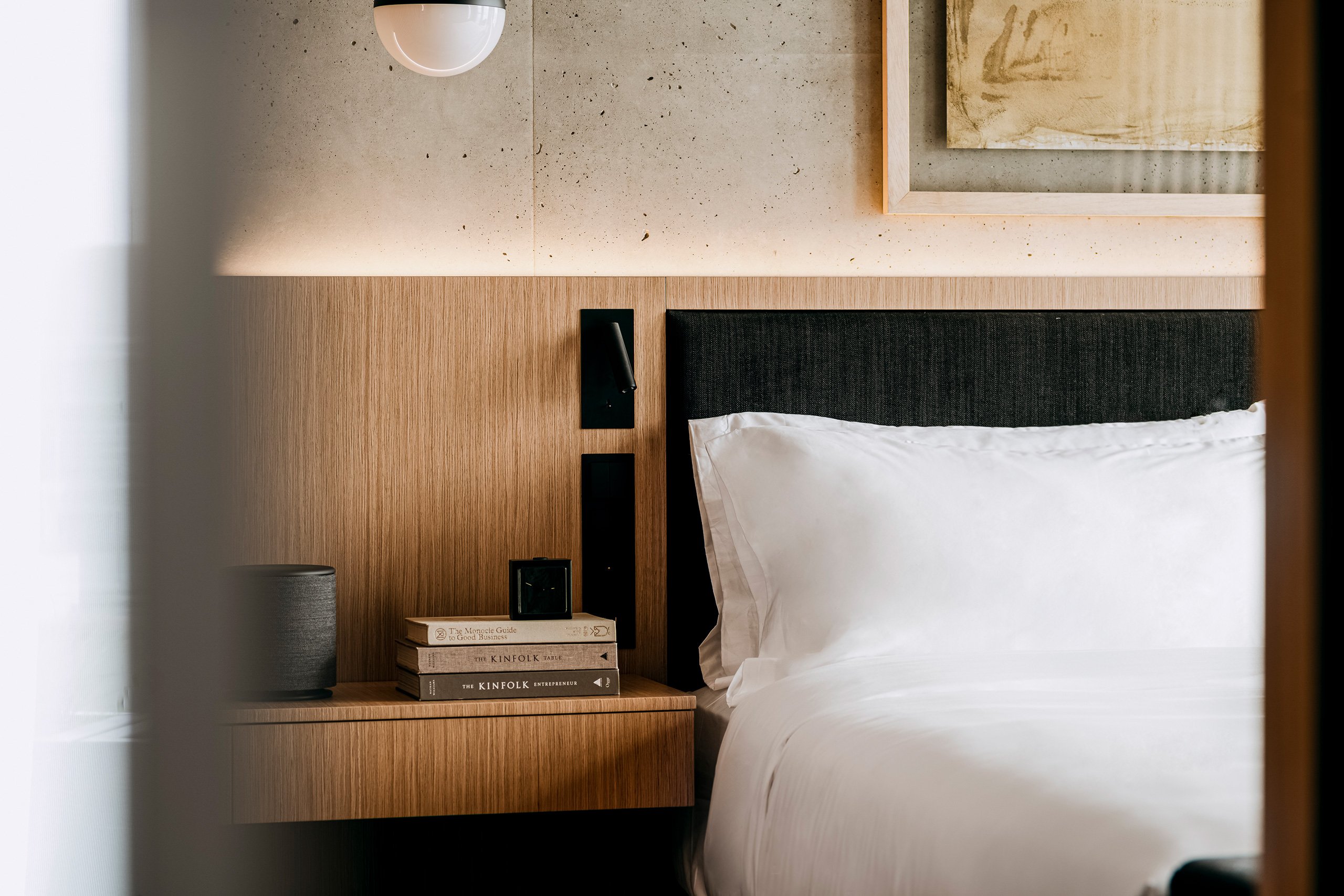 Cozy hotel room featuring a bed, nightstand, and a beautiful painting on the wall.