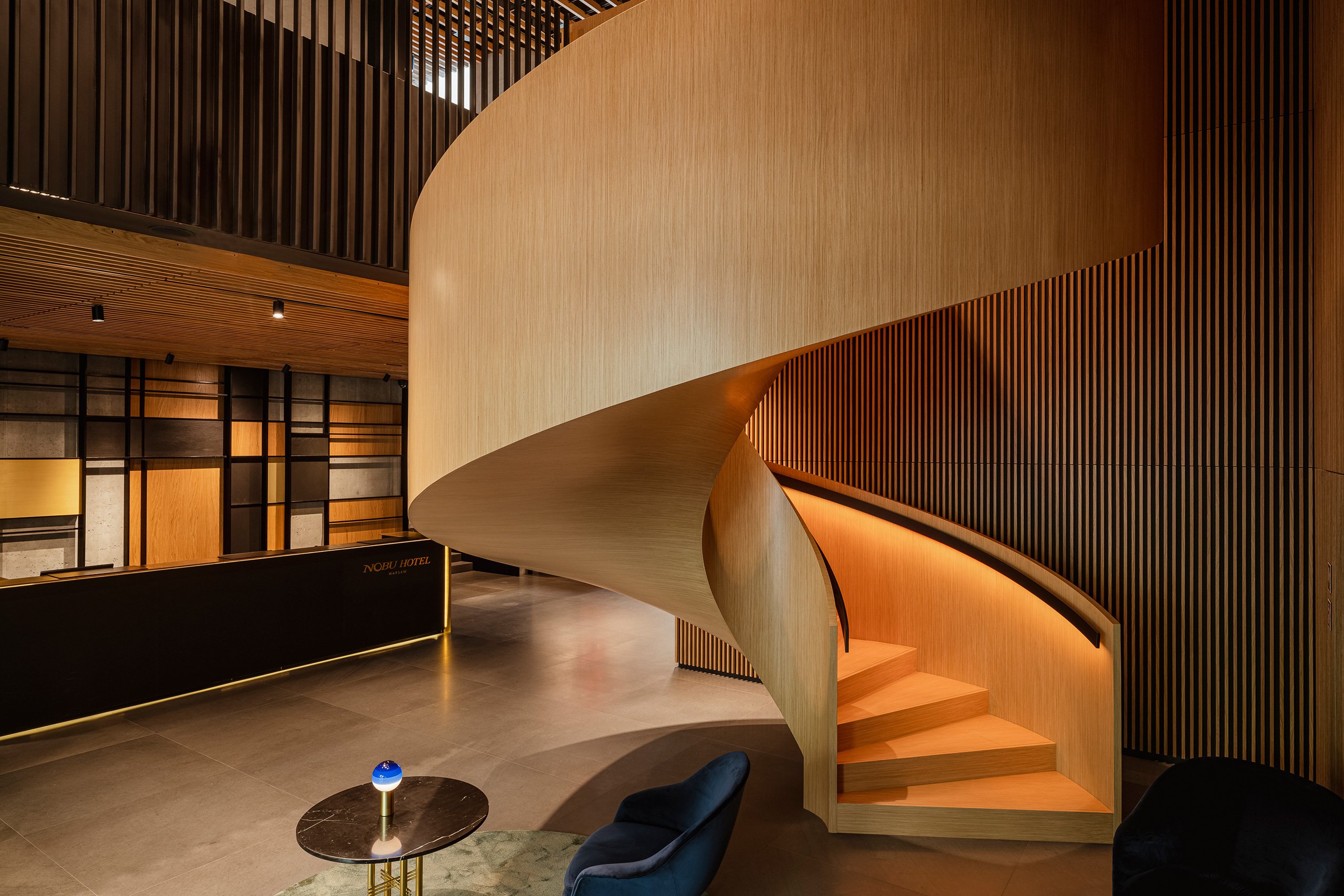 A stylish spiral staircase spirals upward in a chic hotel lobby, enhancing the modern aesthetic of the space.