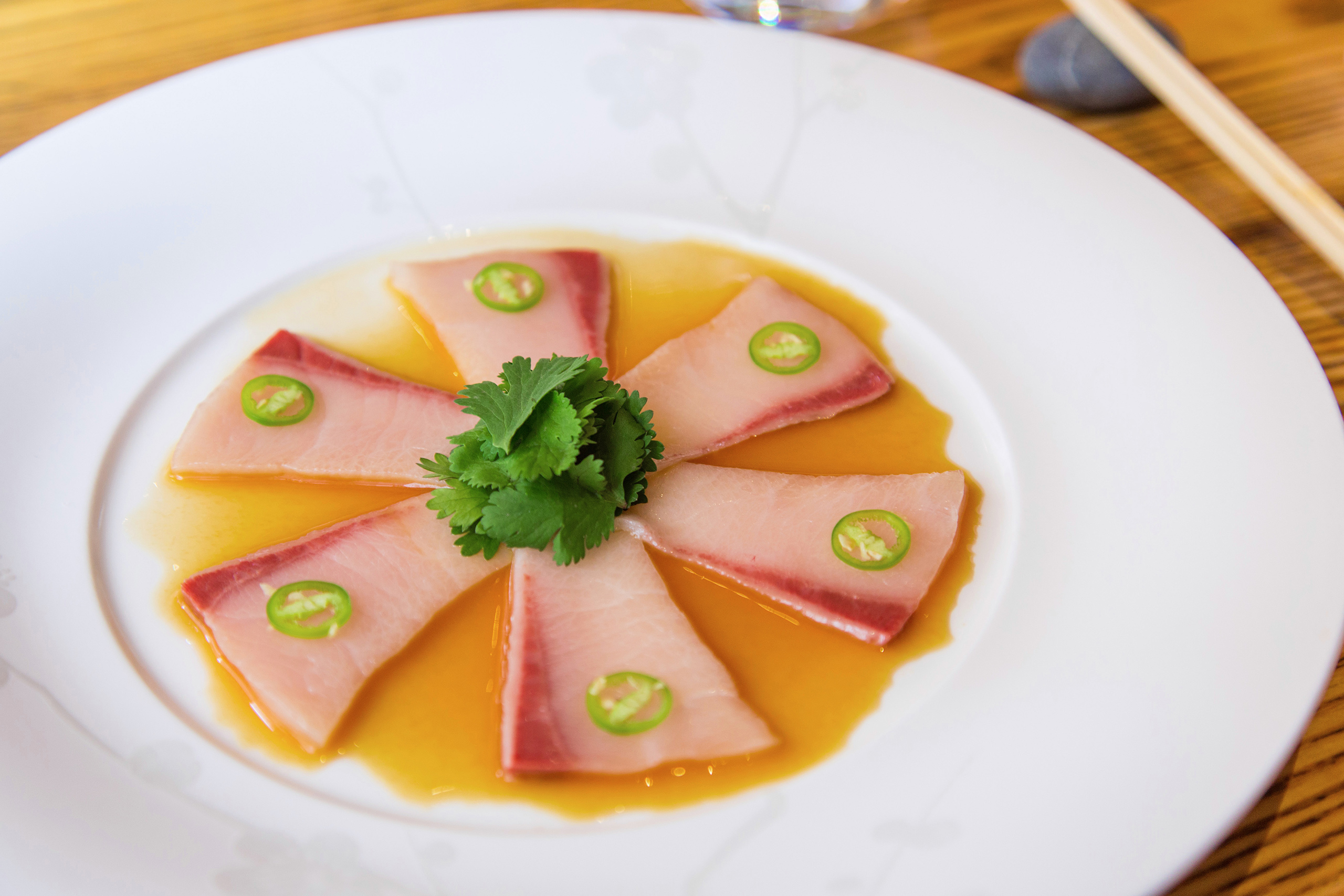 A plate of colorful sushi rolls with a pair of chopsticks