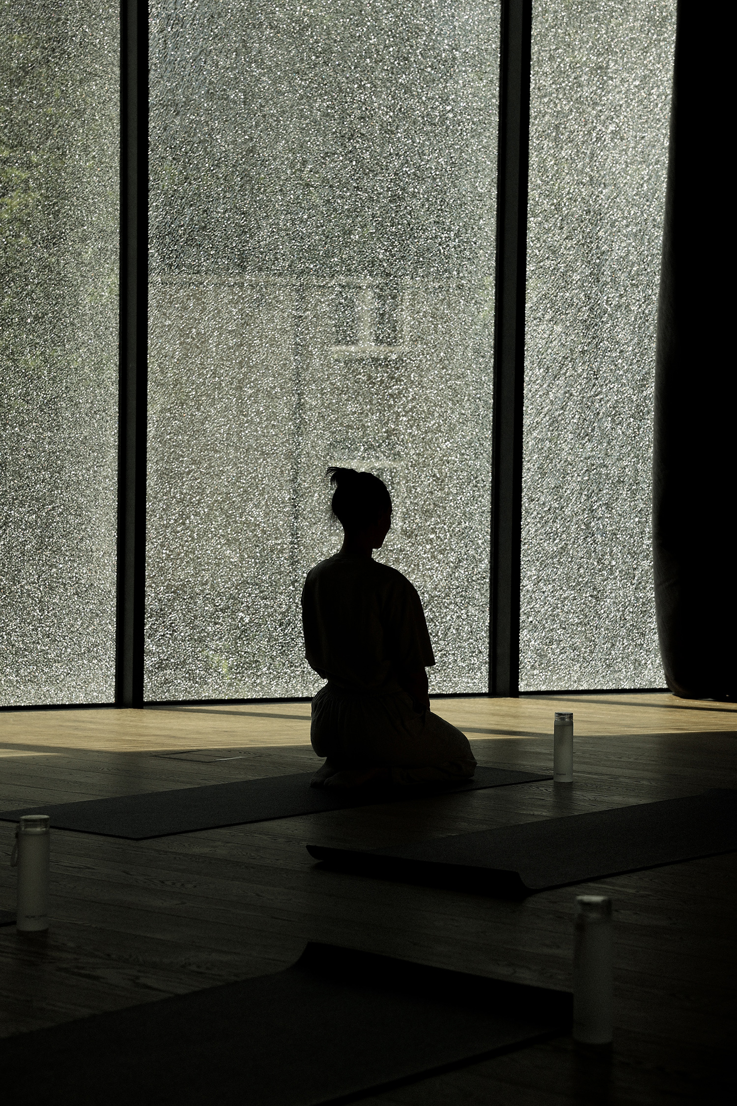 A woman is seated in a room, with a large window